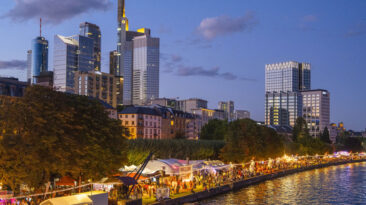 Aufnahme der Beleuchteten Buden am Frankfurter Mainufer in der Dämmerung. Im Hintergrund die Hochhäuser der Frankfurter Skyline.