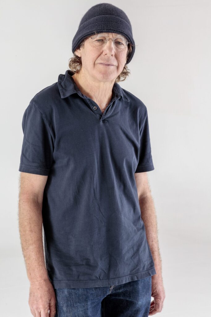 Portrait von Charles Ray stehend. Ray trägt ein blaues T-Shirt, eine blaue Mütze und blickt in die Kamera. Seine Arme hängen seitlich.